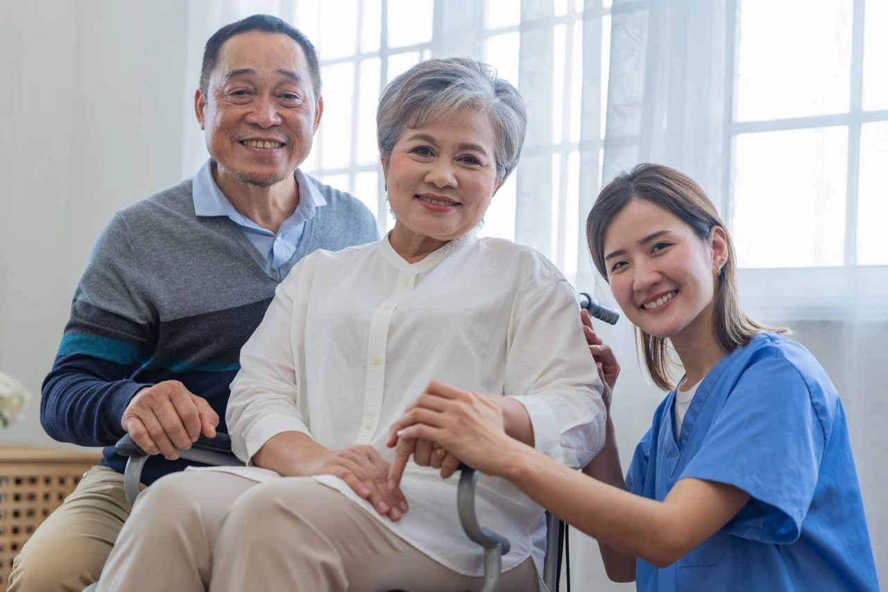Professional caregiver smiling in uniform with seniors receiving home care services